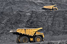 Construction dump trucks travel through mining operation.